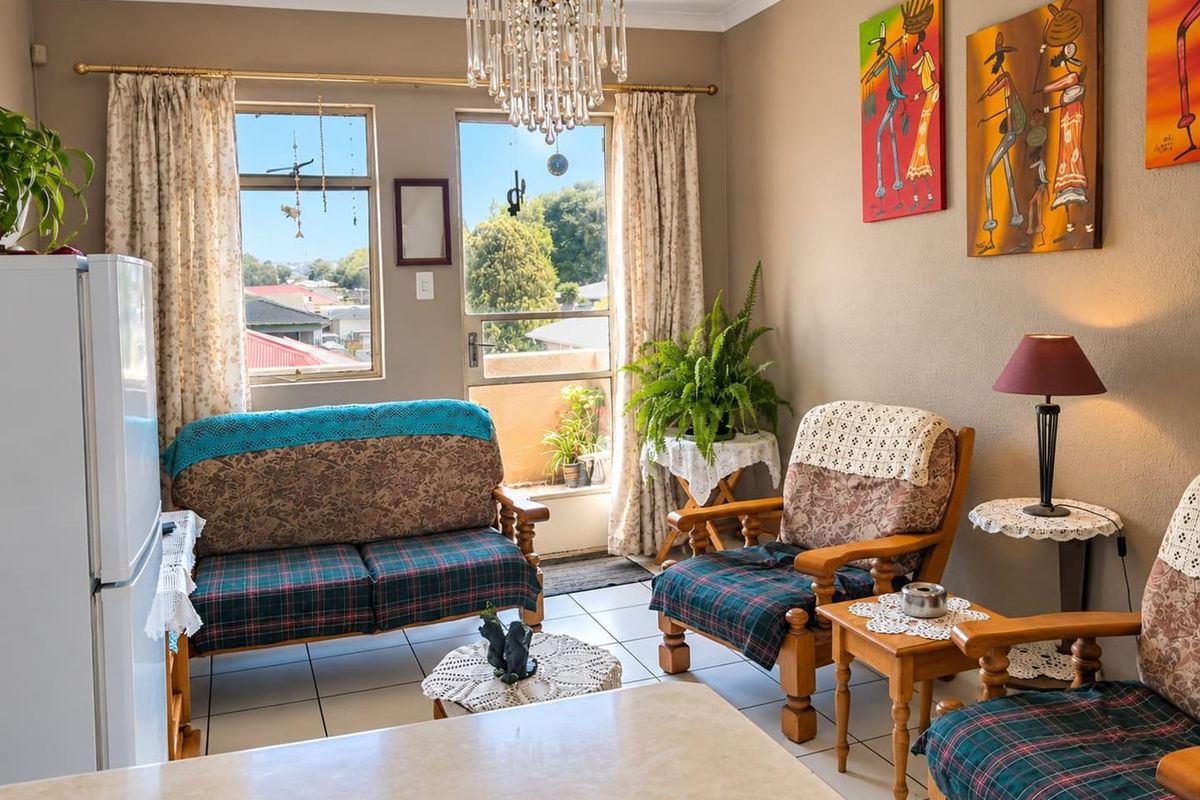 Open plan living area featuring tiled flooring, a decorative crystal chandelier, and direct access to a balcony through a sliding glass door.