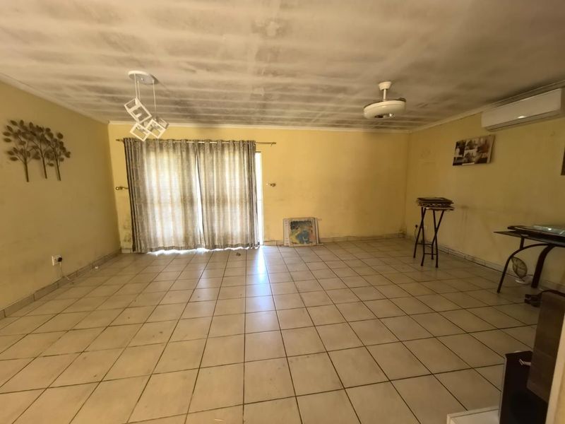 Spacious living area featuring tiled flooring, a ceiling fan, and a split-system air conditioner, with direct access to the outdoors via sliding glass doors.