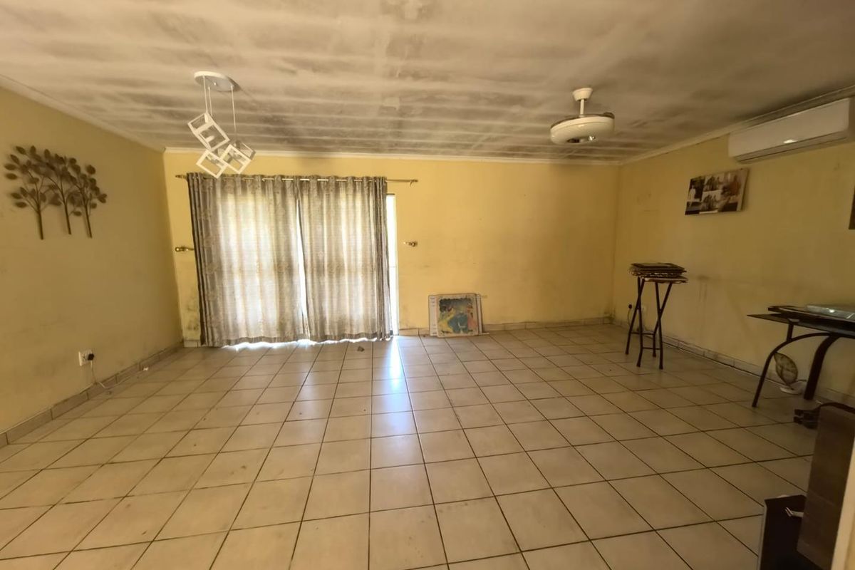 Spacious living area featuring tiled flooring, a ceiling fan, and a split-system air conditioner, with direct access to the outdoors via sliding glass doors.