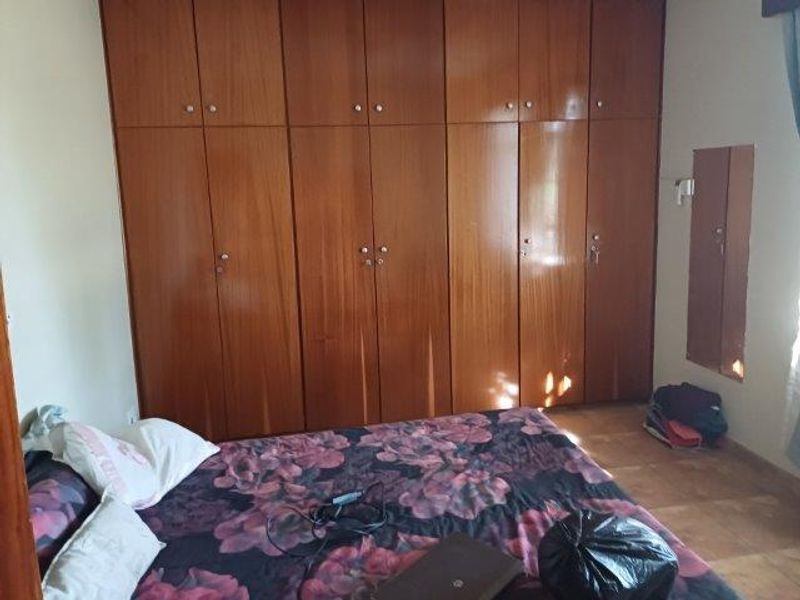 A bedroom featuring extensive floor-to-ceiling built-in wooden wardrobes providing ample storage space.