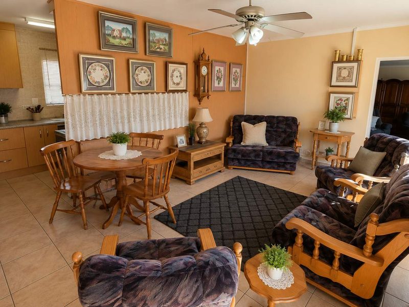 Open-plan living and dining area featuring tiled floors, a ceiling fan, and an adjoining kitchen with wood-finish cabinetry and laminate countertops.