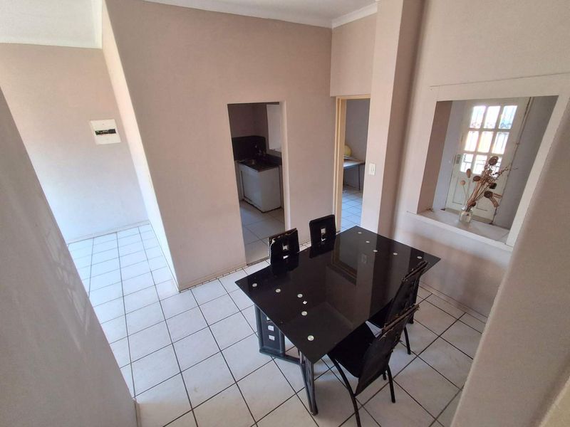 A dining area featuring tiled flooring and an internal window, with direct access to an adjacent kitchen and hallway.