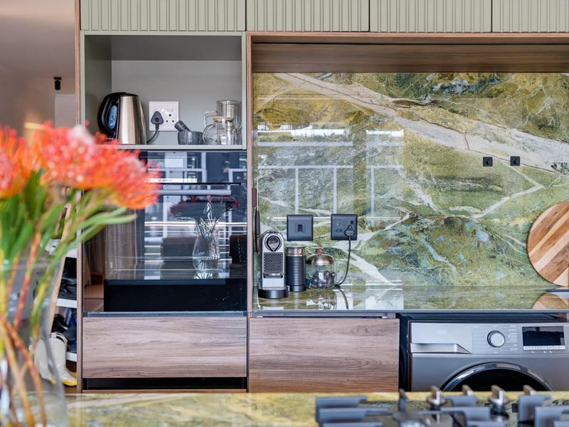 Modern kitchen featuring high-end stone splashback, integrated appliances, and custom cabinetry with a sleek, contemporary finish.
