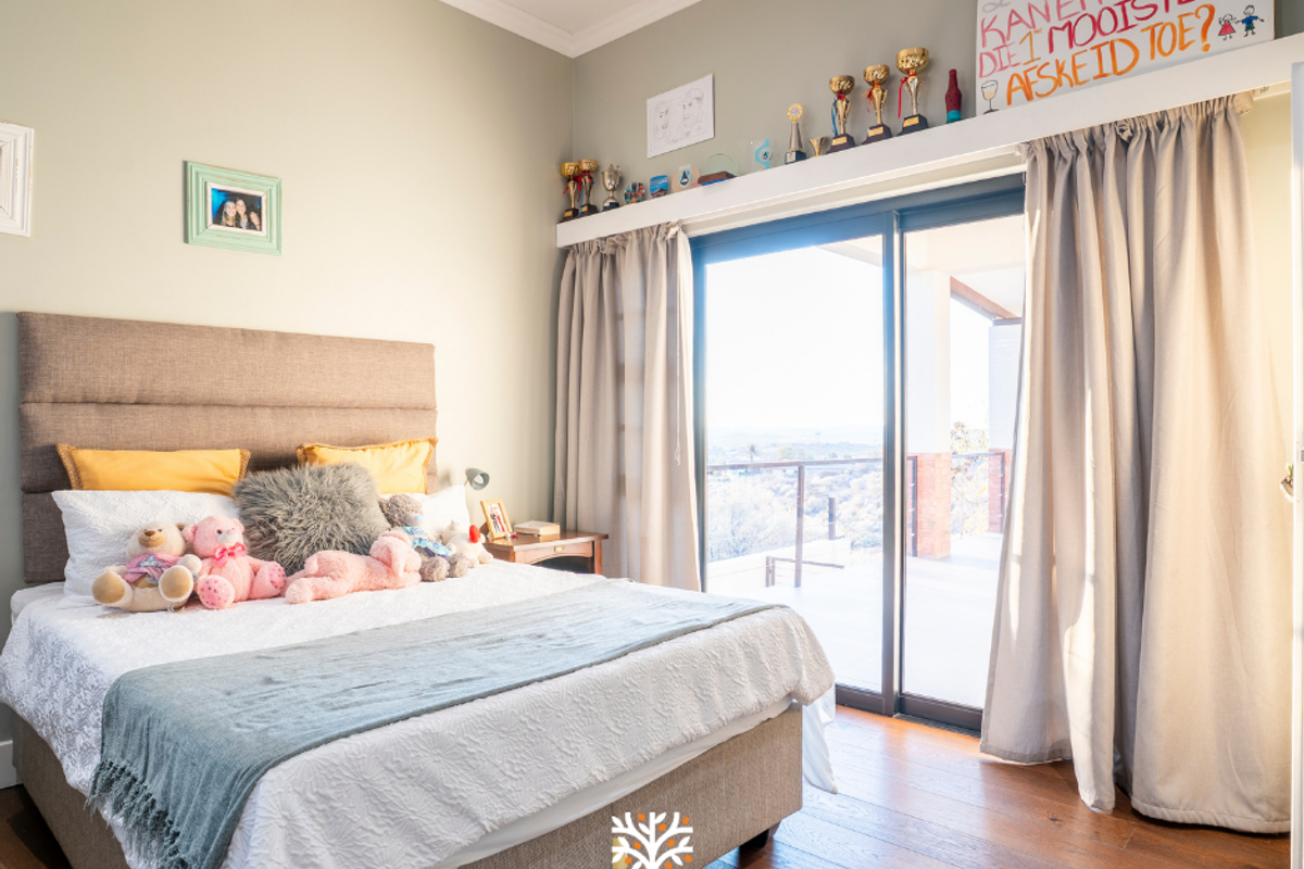 A well-maintained bedroom featuring timber flooring, a split-system air conditioner, and large sliding glass doors providing access to an outdoor area.