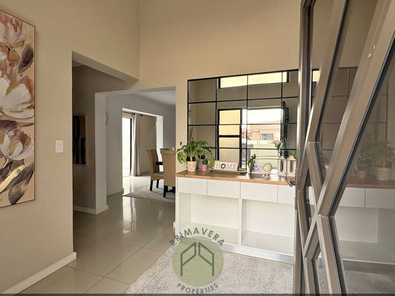 Welcoming entrance hall featuring high ceilings, polished tiled flooring, and a decorative grid-pattern mirror with a built-in console unit.