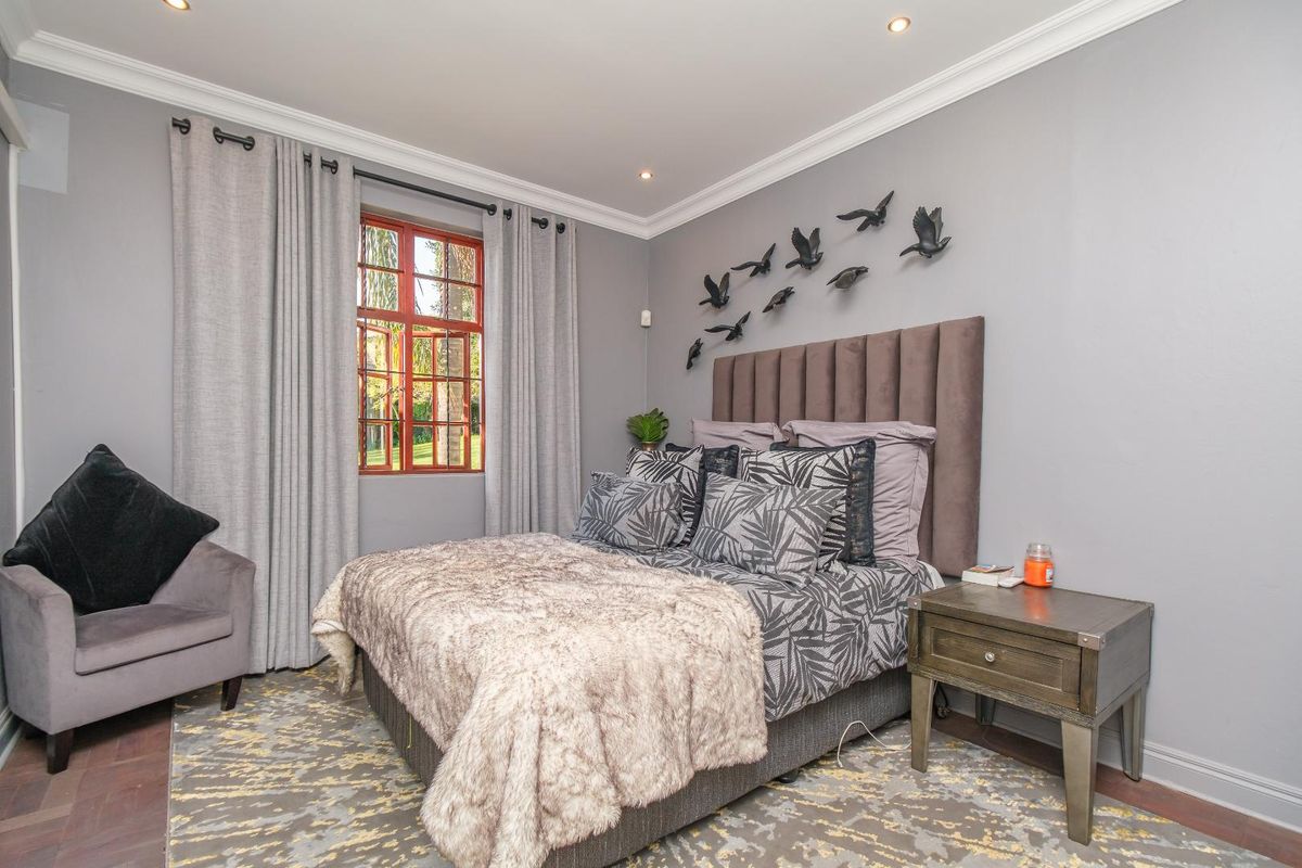 A well-maintained bedroom featuring crown molding, recessed downlights, and a large window with timber frames, providing a comfortable and inviting living space.