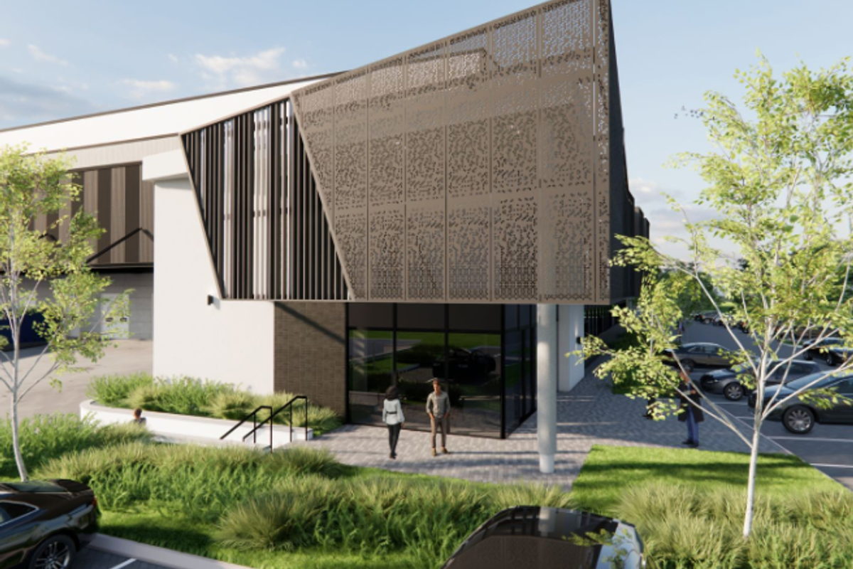 Modern industrial building exterior featuring a striking perforated metal facade, glass entrance, and landscaped parking area.