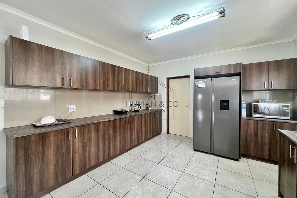 A functional kitchen featuring wood-grain cabinetry, tiled flooring, and a dedicated space for a double-door refrigerator.