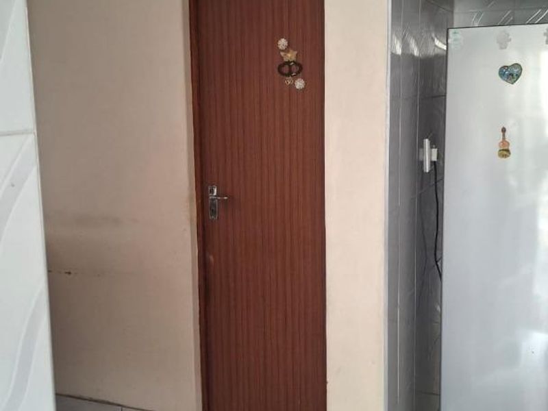 A functional hallway area featuring tiled flooring, wall tiling, and an arched doorway leading to an adjacent room.