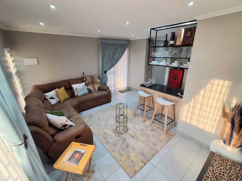 Open plan living area featuring tiled flooring, recessed lighting, and a built-in bar counter with integrated shelving.