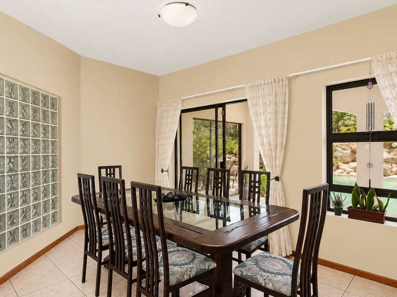 A bright dining room featuring a glass block accent wall, tiled flooring, and sliding doors providing direct access to the outdoor pool area.