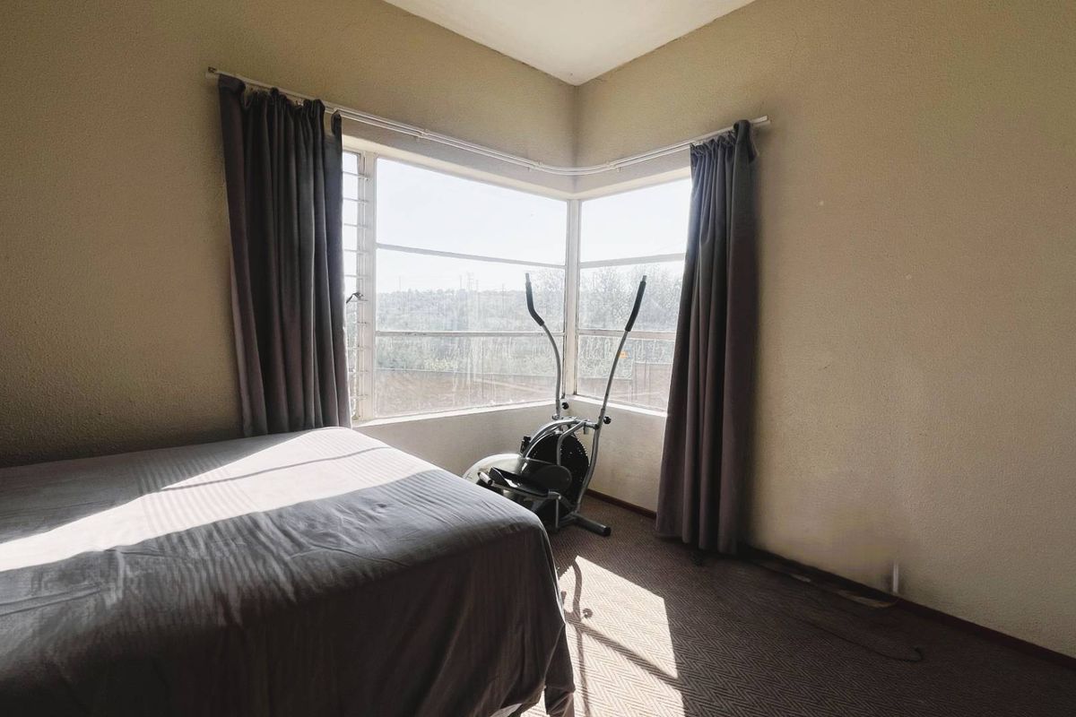 A bedroom featuring a corner window with natural light, carpeted flooring, and neutral wall finishes.