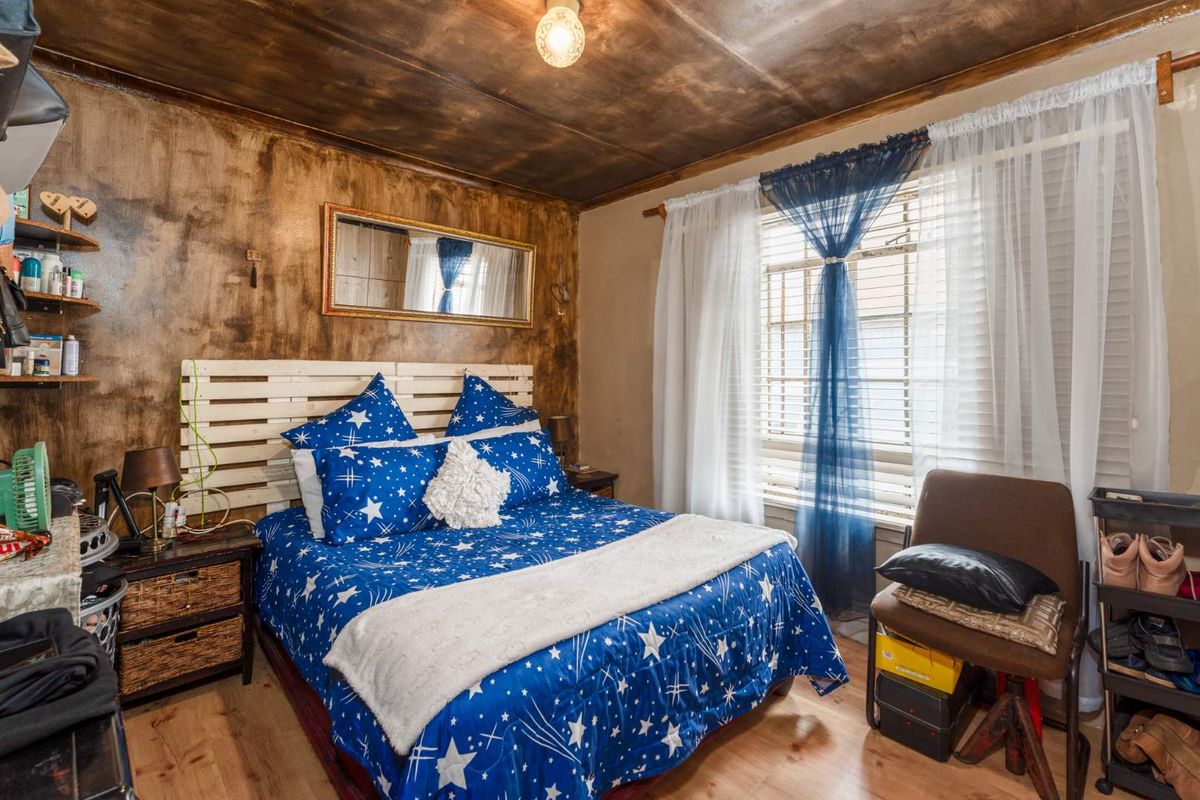 A bedroom featuring laminated flooring and a timber-look ceiling, offering a functional space with potential for cosmetic updates.