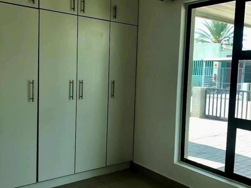 A clean, empty bedroom featuring neutral tiled flooring and extensive floor-to-ceiling built-in cupboards, offering ample storage space.