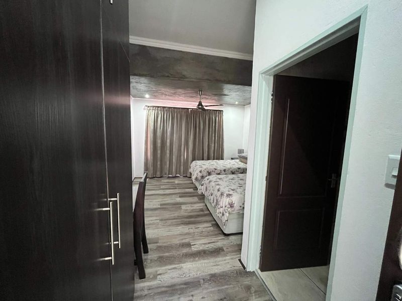 A bedroom featuring laminate flooring, a ceiling fan, and a built-in wardrobe, with a neutral color palette and modern finishes.