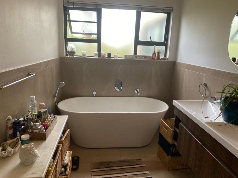 A modern bathroom featuring a freestanding bathtub, wall-mounted mixer tap, and a contemporary vanity unit with integrated basin.