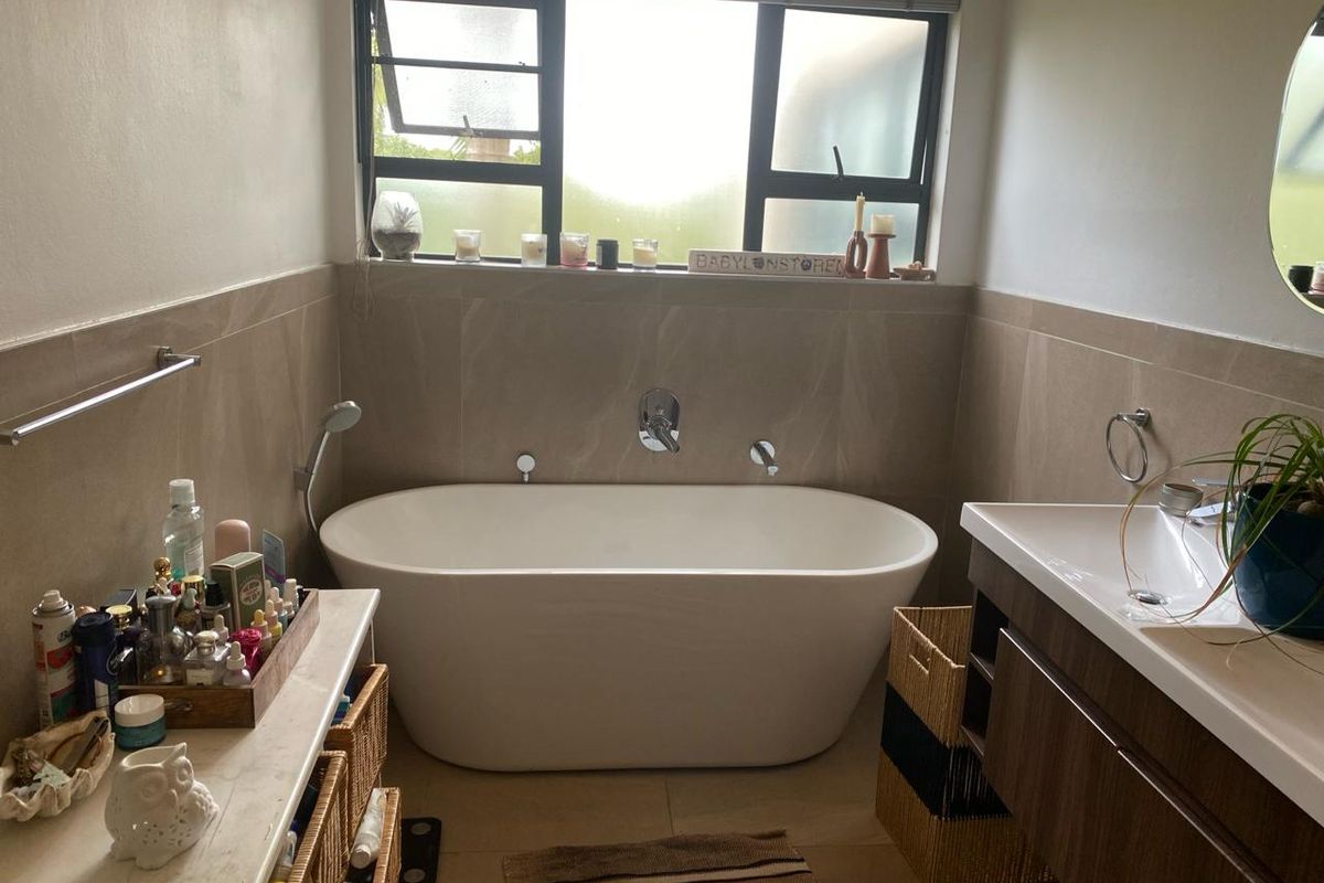 A modern bathroom featuring a freestanding bathtub, wall-mounted mixer tap, and a contemporary vanity unit with integrated basin.