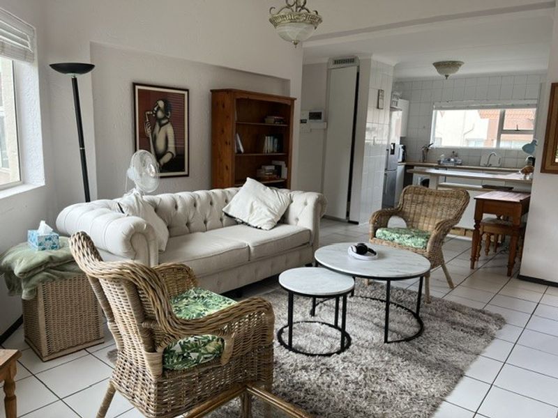 Open plan living area featuring tiled flooring and a connected kitchen space with built-in cabinetry and sink.