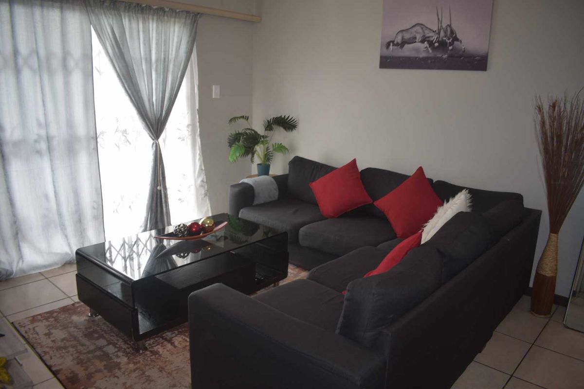 A comfortable living room featuring tiled flooring and large sliding glass doors that provide access to the outdoor area.