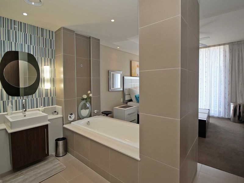 Modern open-plan bathroom featuring a built-in bathtub and vanity, seamlessly integrated with the adjacent bedroom area.