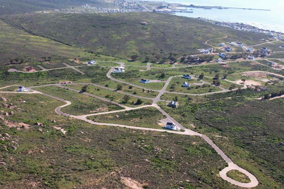 Aerial view of a residential estate development featuring paved roads, established infrastructure, and scattered homes set within a natural coastal landscape.