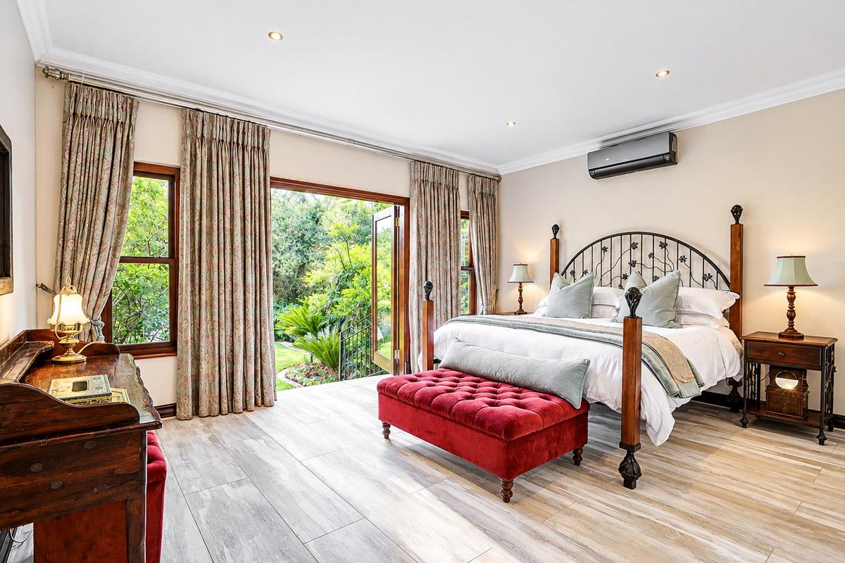 Spacious bedroom featuring timber-look tile flooring, recessed lighting, split-system air conditioning, and direct access to the garden through double doors.