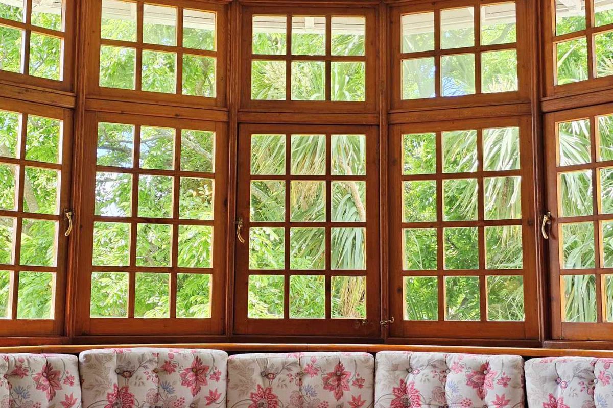 A bright living area featuring a large, classic timber-framed bay window that provides expansive views of the surrounding garden greenery.
