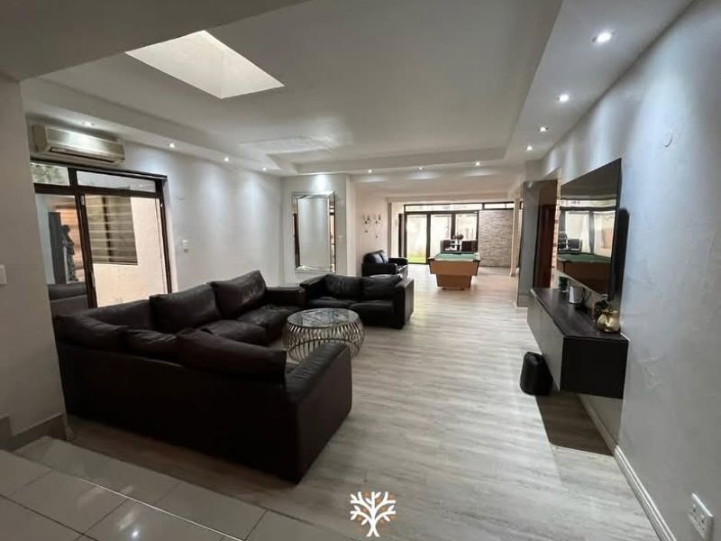 Spacious open-plan living area featuring modern laminate flooring, recessed lighting, a skylight, and split-system air conditioning with seamless access to outdoor spaces.