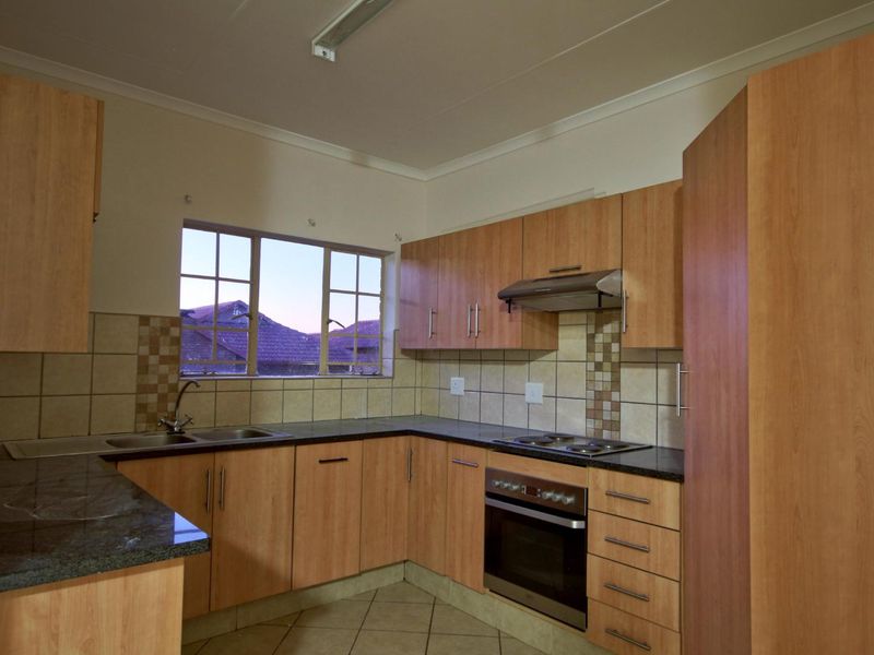 A functional kitchen featuring laminate cabinetry, granite countertops, a built-in oven with hob, and tiled backsplash, offering a clean and practical workspace.