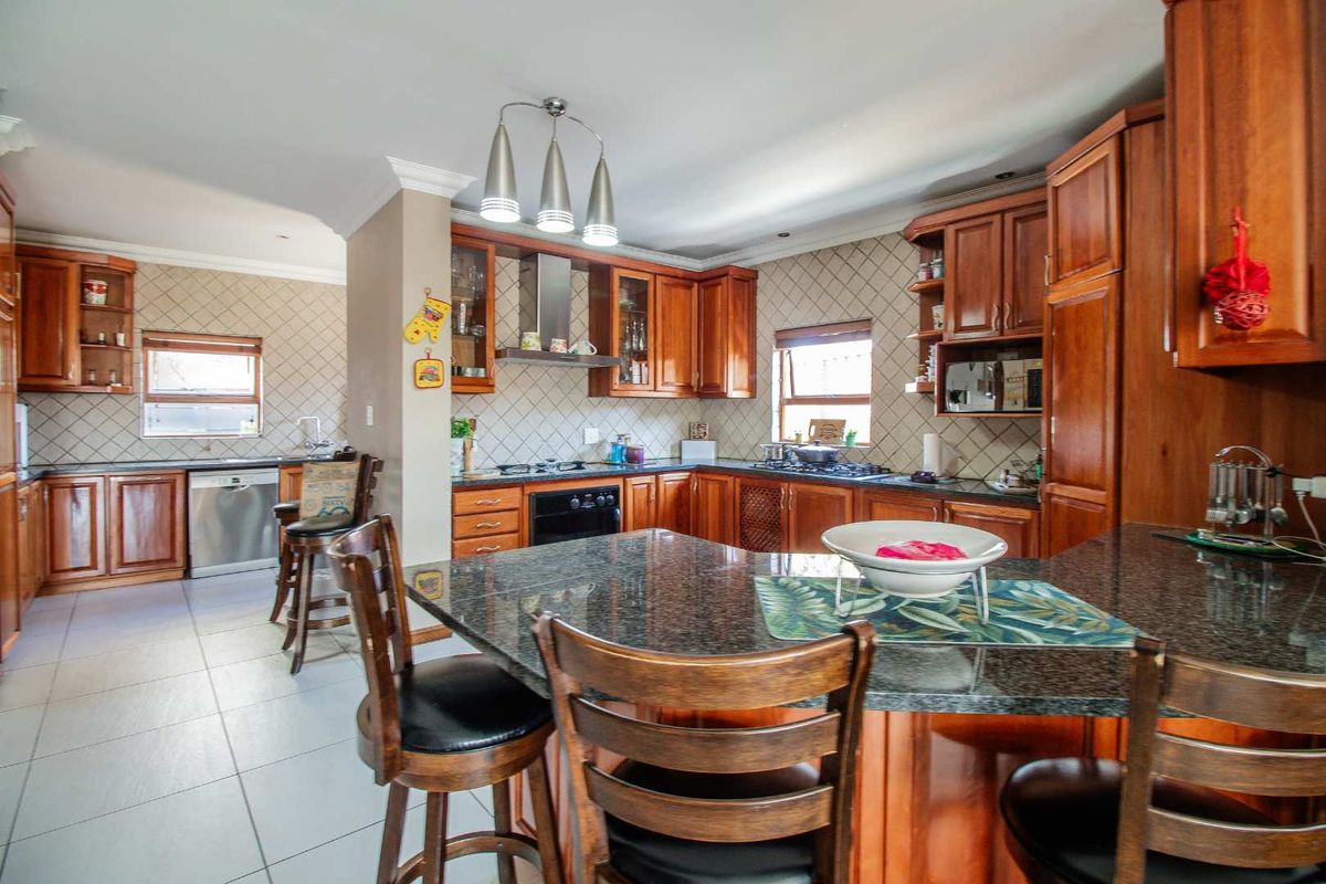 Spacious kitchen featuring dark wood cabinetry, granite countertops, a breakfast bar, and tiled backsplash, offering ample storage and workspace.