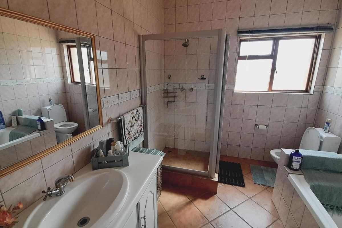 A functional bathroom featuring a built-in vanity, separate shower enclosure, bathtub, and toilet, finished with neutral wall and floor tiling.