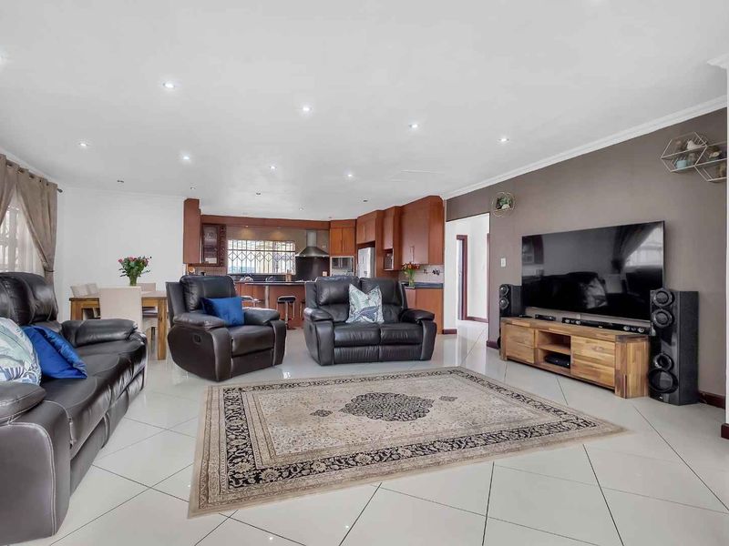 Spacious open-plan living area featuring tiled floors, recessed lighting, and a functional kitchen with built-in cabinetry and an island.