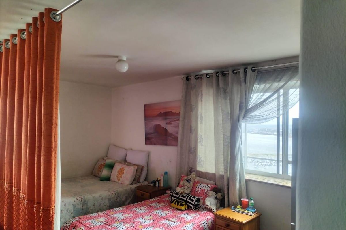 A bedroom featuring a window with natural light and a curtain partition, offering a functional space with a view.
