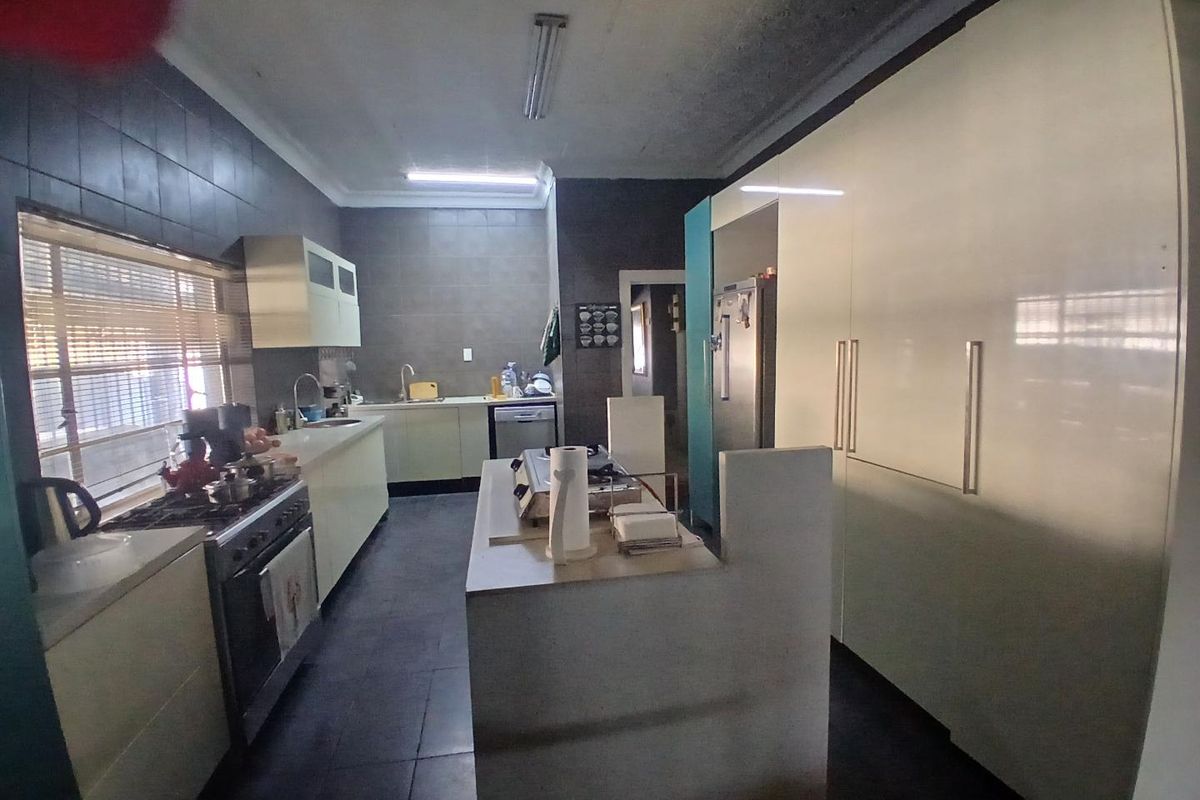 A functional kitchen featuring a central island, built-in cabinetry, gas stove, and tiled finishes, offering a practical layout with potential for modern updates.