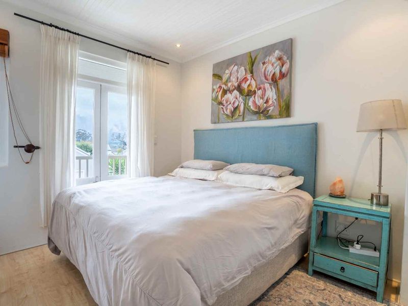 A bright and well-maintained bedroom featuring light timber-look flooring, a tongue and groove ceiling, and direct access to a balcony through french doors.