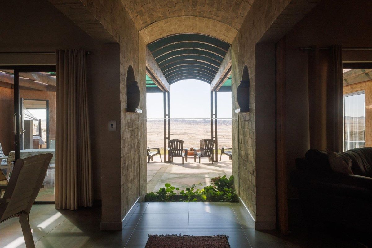 A view from the interior through a vaulted stone archway leading to a covered patio overlooking an expansive landscape.
