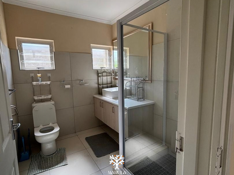 A functional bathroom featuring a shower enclosure, vanity cabinet with a vessel sink, and tiled finishes throughout.
