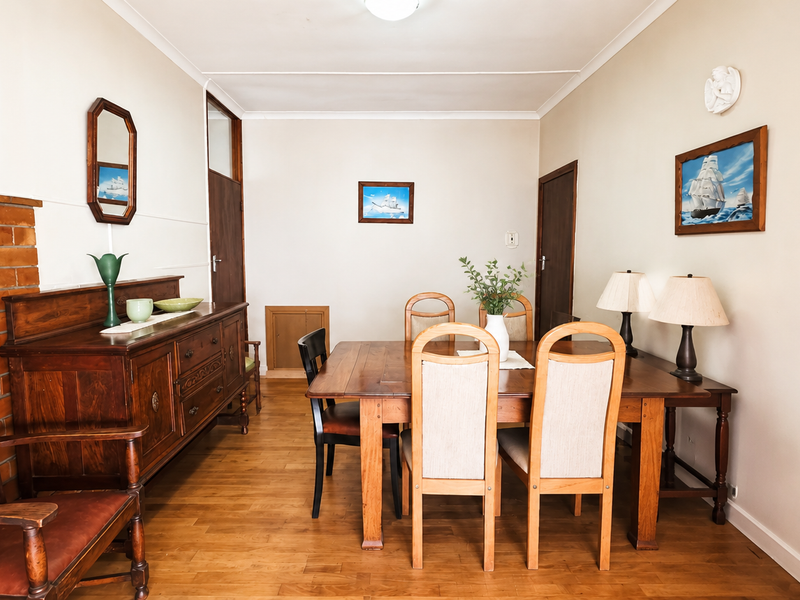 A dining room featuring hardwood flooring, a coved ceiling, and an exposed brick feature wall, providing a warm and traditional atmosphere.