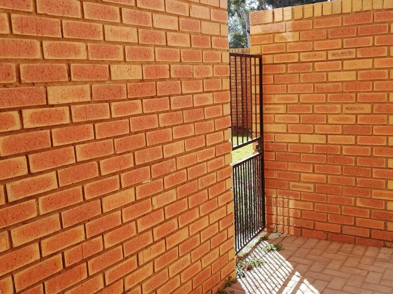 A private rear courtyard area featuring exposed brick walls, paved flooring, and a secure metal gate providing access to the exterior.