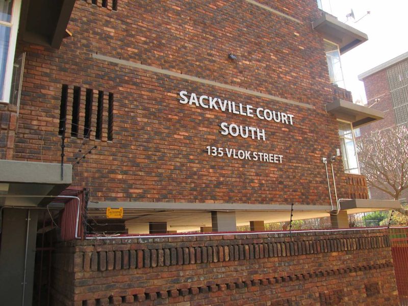 Exterior view of the Sackville Court South apartment building facade, featuring face brick construction and secure perimeter fencing.