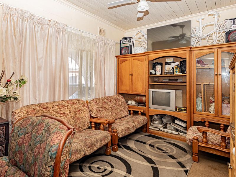 A living room featuring a timber-look ceiling, ceiling fan, and extensive built-in wooden cabinetry for storage and display.