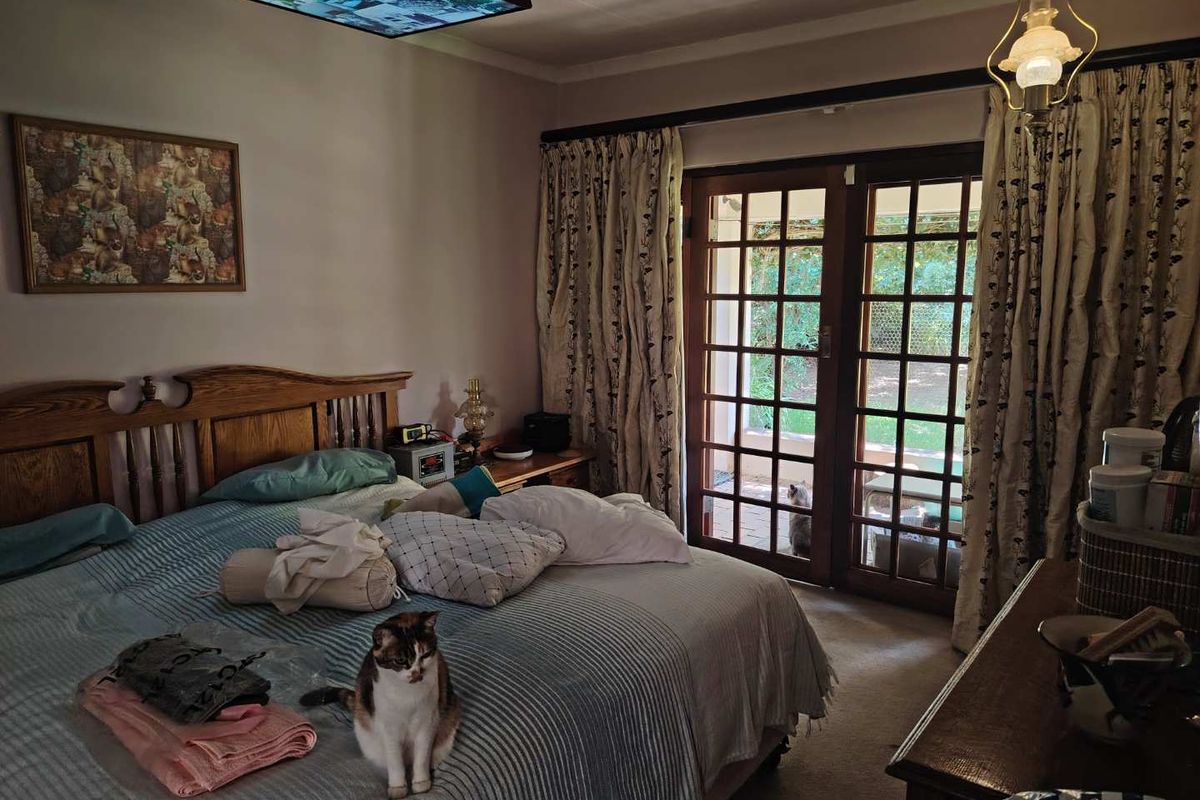A bedroom featuring wooden door frames with glass panels leading to an outdoor patio area, providing natural light and garden access.