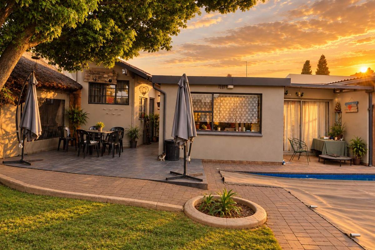 Rear exterior view featuring a tiled patio area, swimming pool with paved surround, and a mix of modern and traditional architectural elements at sunset.