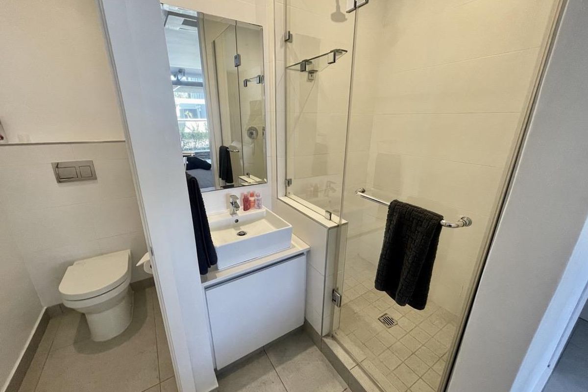 Modern bathroom featuring a wall-mounted toilet, a vessel sink vanity, and a glass-enclosed walk-in shower with tiled flooring.