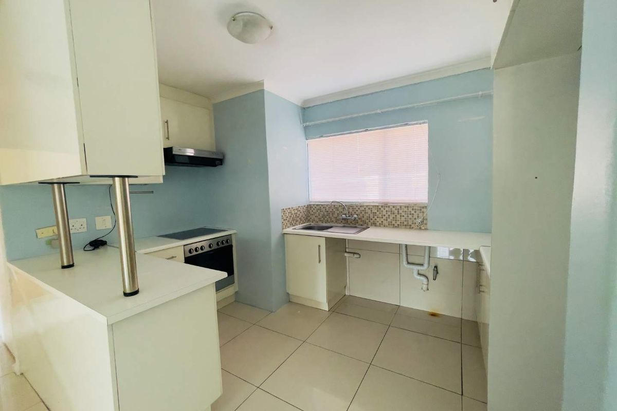 A functional kitchen featuring built-in cabinetry, an electric oven and hob, extractor fan, and tiled flooring with a mosaic backsplash.