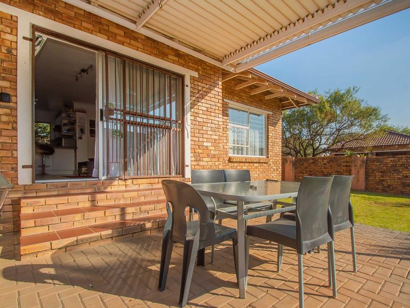 A covered brick-paved patio area featuring a sliding door entrance, providing a functional outdoor space for relaxation and entertaining.
