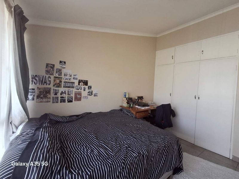 A bedroom featuring built-in cupboards and tiled flooring, offering a functional space with neutral wall tones.