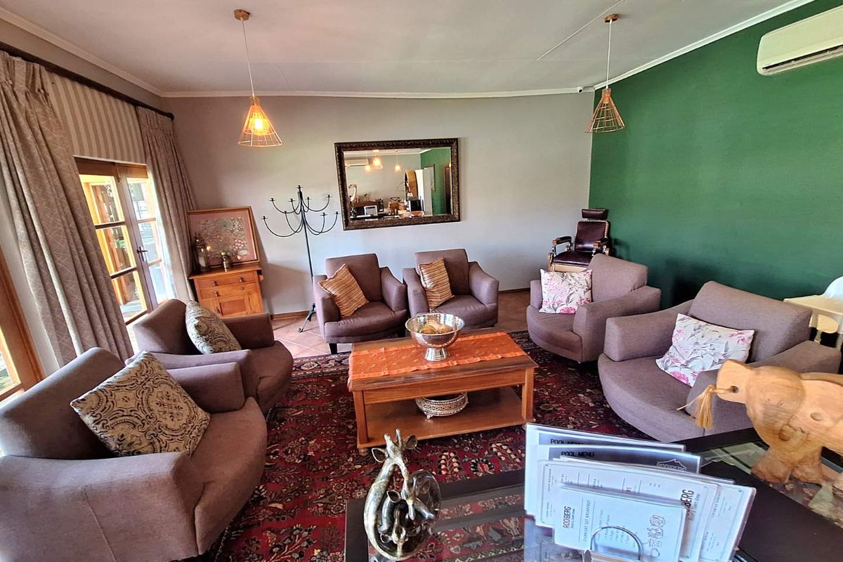 A comfortable living room area featuring a split-system air conditioning unit, pendant lighting, and access to an outdoor patio through glass doors.