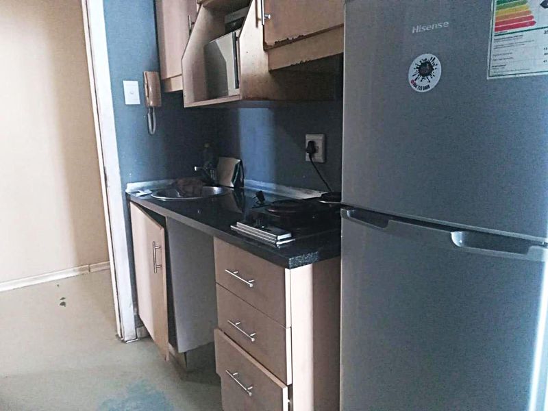Compact kitchen area featuring built-in cabinetry, a laminate countertop, and a stainless steel sink, showing signs of wear and requiring maintenance.