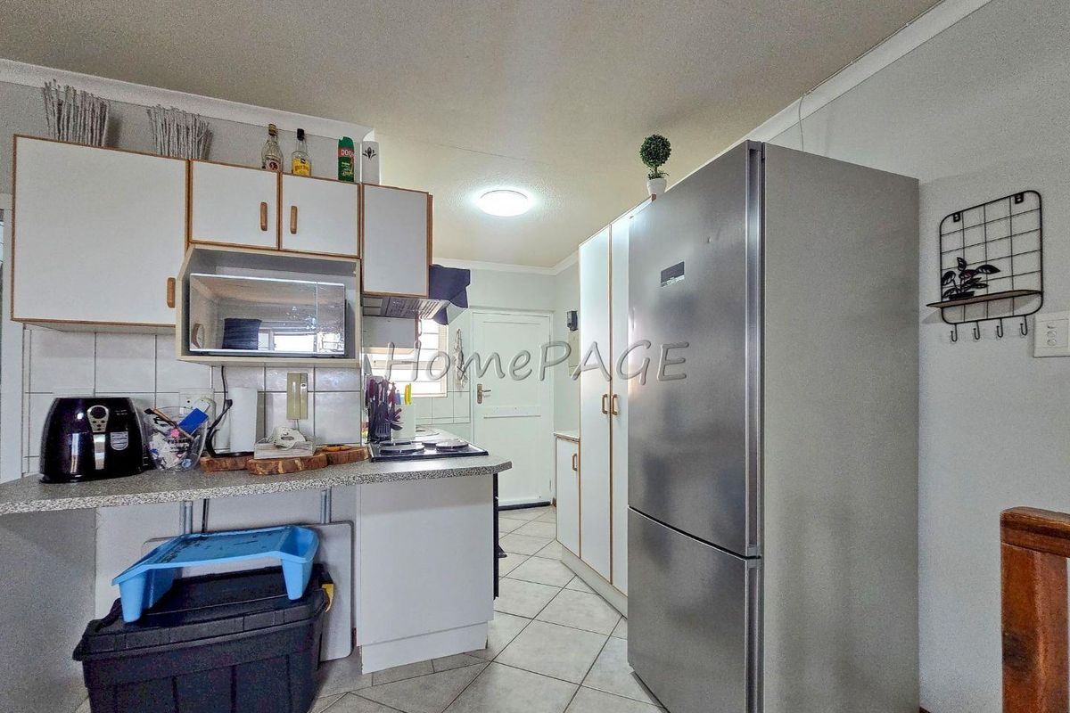 A functional kitchen featuring white cabinetry, tiled flooring, and built-in counter space, providing a practical layout for daily meal preparation.